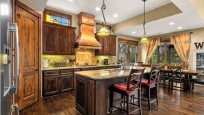 A spacious kitchen with wooden cabinets, a large island, and bar stools.
