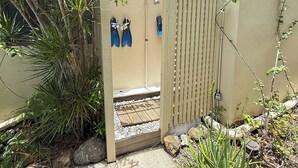 A wooden gate leading to a covered area with a shower and a towel rack.
