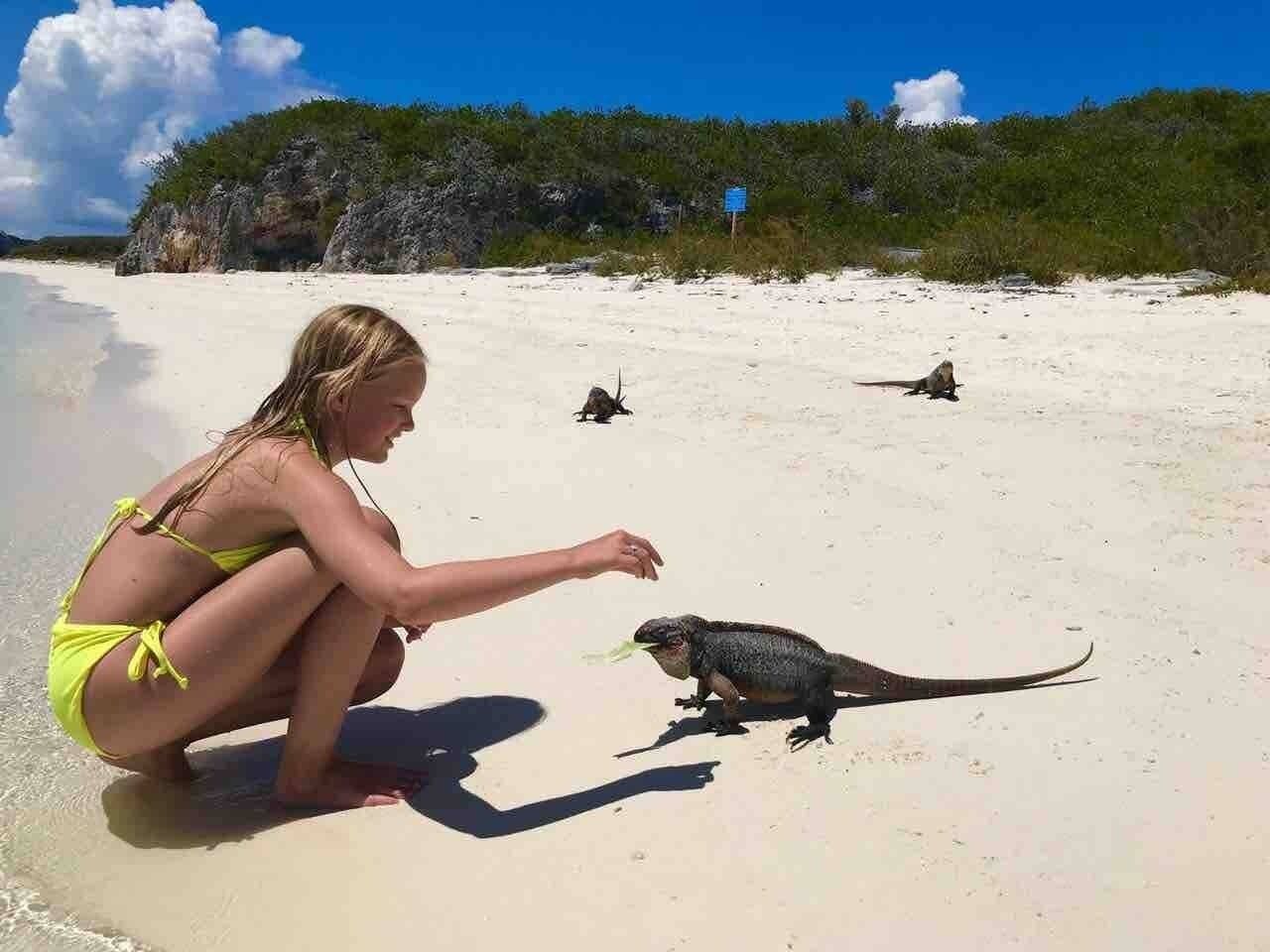 Een persoon in een gele bikini op een zandstrand met een zeeschildpad.