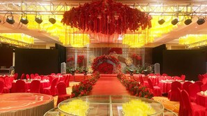 A banquet hall with round tables covered in red tablecloths, a central aisle with red flowers, and a glass railing. - Days Hotel & Suites by Wyndham Jiangsu Xinyi (Xuzhou)