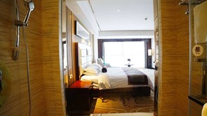 A hotel room with a bed, a bedside table, a shower, and a view of the outside. - Days Hotel & Suites by Wyndham Jiangsu Xinyi (Xuzhou)