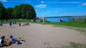 En sandstrand med mennesker, cykler og strandlegetøj.