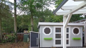 Et lille hus i et etage med en overdækket veranda, en indhegnet have og et skur.