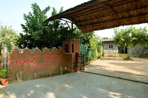 Schild für Bagh Dera Resort, im Hintergrund ein Steinhaus.
