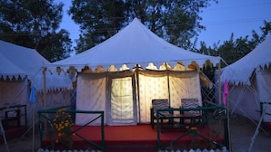Una carpa blanca con alfombra roja y dos sillas.
