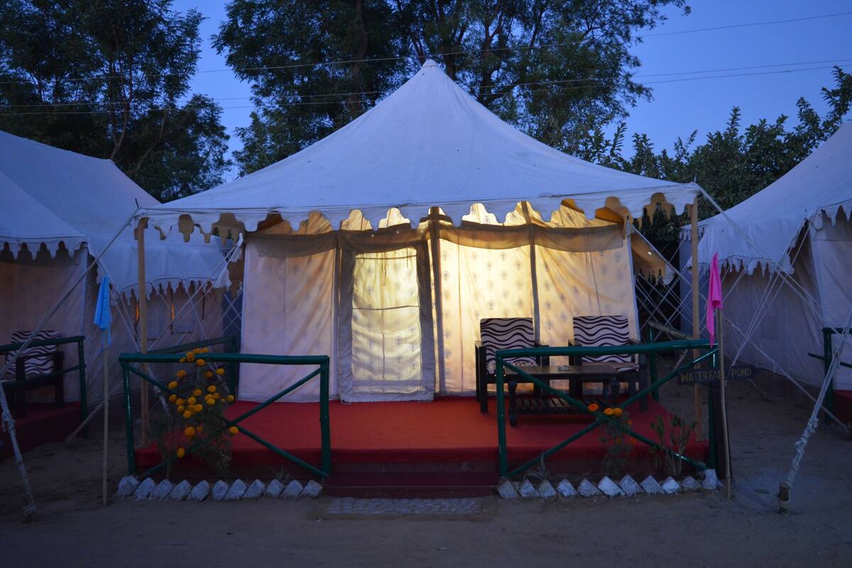A white tent with a red carpet and two chairs.
