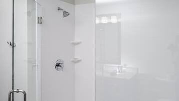 A modern shower enclosure with a glass door, a handheld showerhead, and a handheld showerhead.