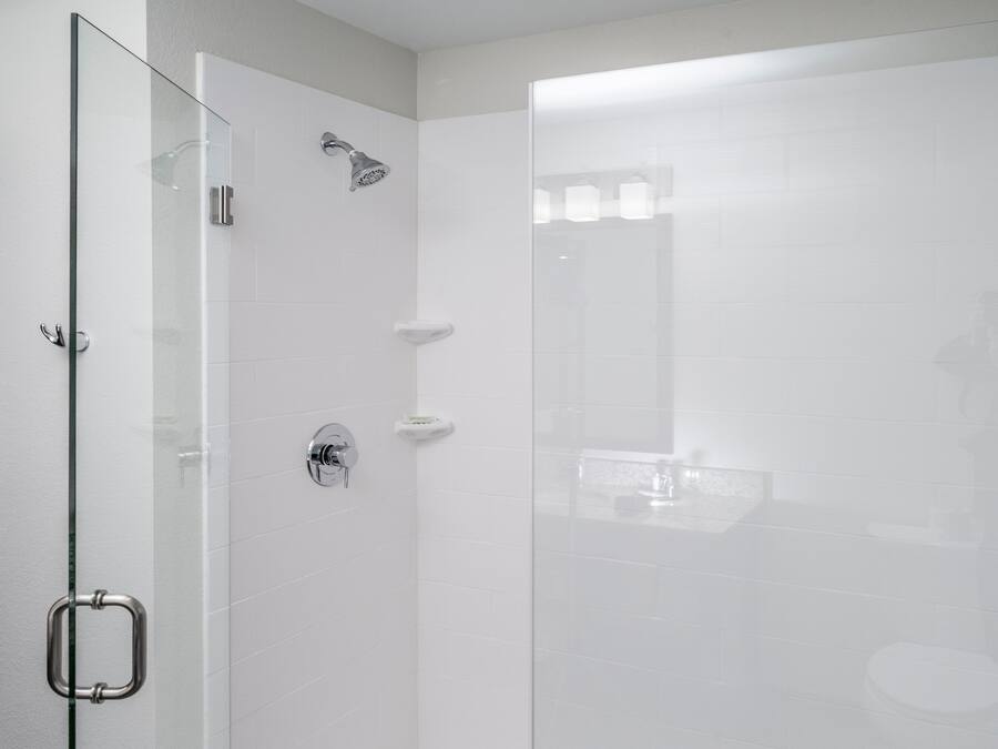 A modern shower enclosure with a glass door, a handheld showerhead, and a handheld showerhead.