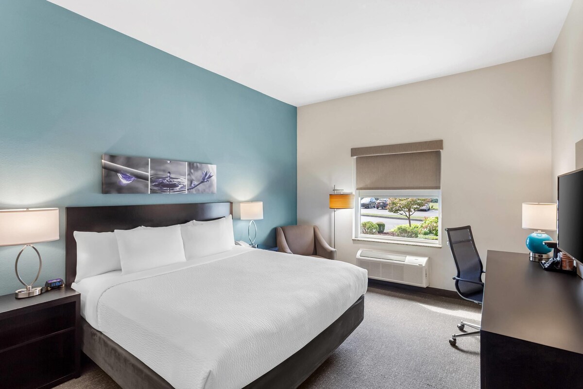 Hotelkamer met een bed, nachtkastjes, een bureau, een stoel, een raam met uitzicht en een wanddecoratie.