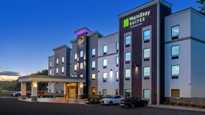 A MainStay Suites hotel with a modern design, featuring a covered entrance and multiple floors. - Sleep Inn Winfield - Teays Valley (Hurricane)