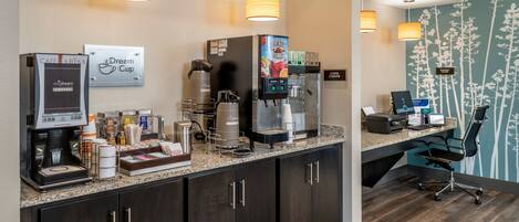 A hotel reception area with a coffee machine, a coffee station, and a sign that reads "Dream Cup."