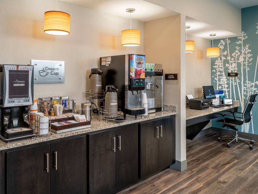 A hotel reception area with a coffee machine, a coffee station, and a sign that reads "Dream Cup."