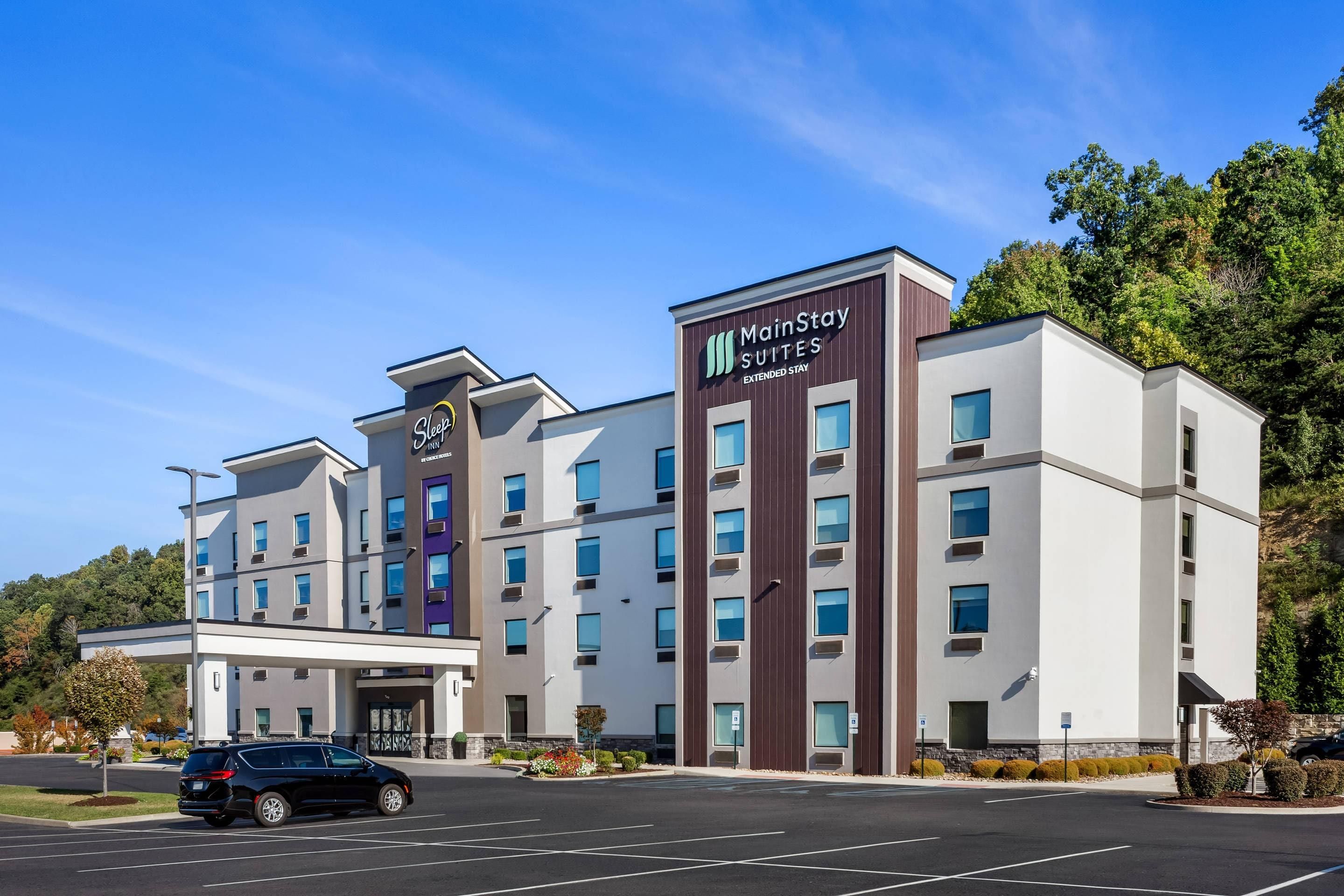 A MainStay Suites extended stay hotel with a modern design, multiple floors, and a parking lot.