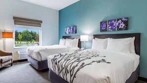 A hotel room with two beds, a desk, a chair, and a window with a view of greenery. - Sleep Inn Winfield - Teays Valley (Hurricane)