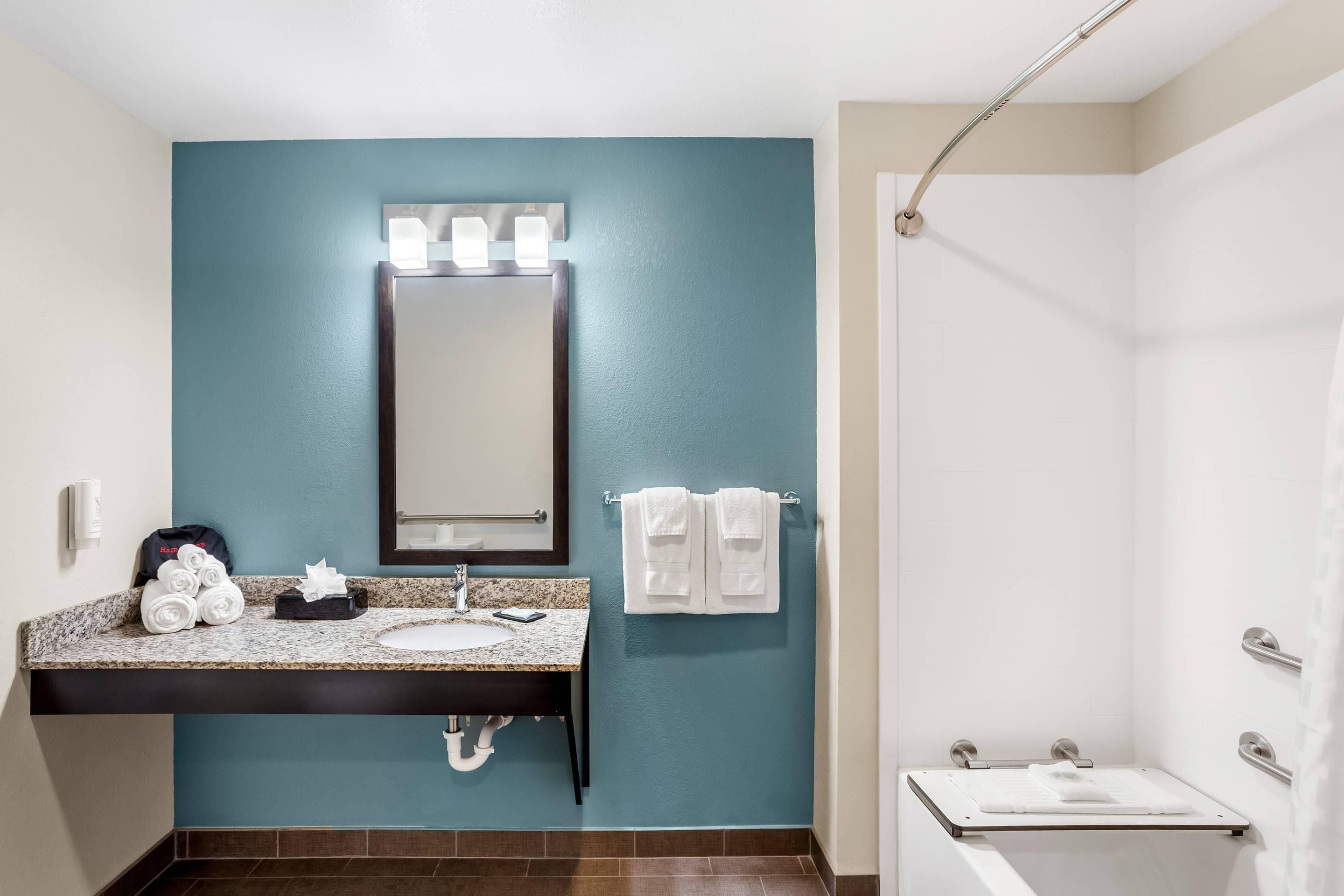 A bathroom with a sink, mirror, towel rack, and shower.