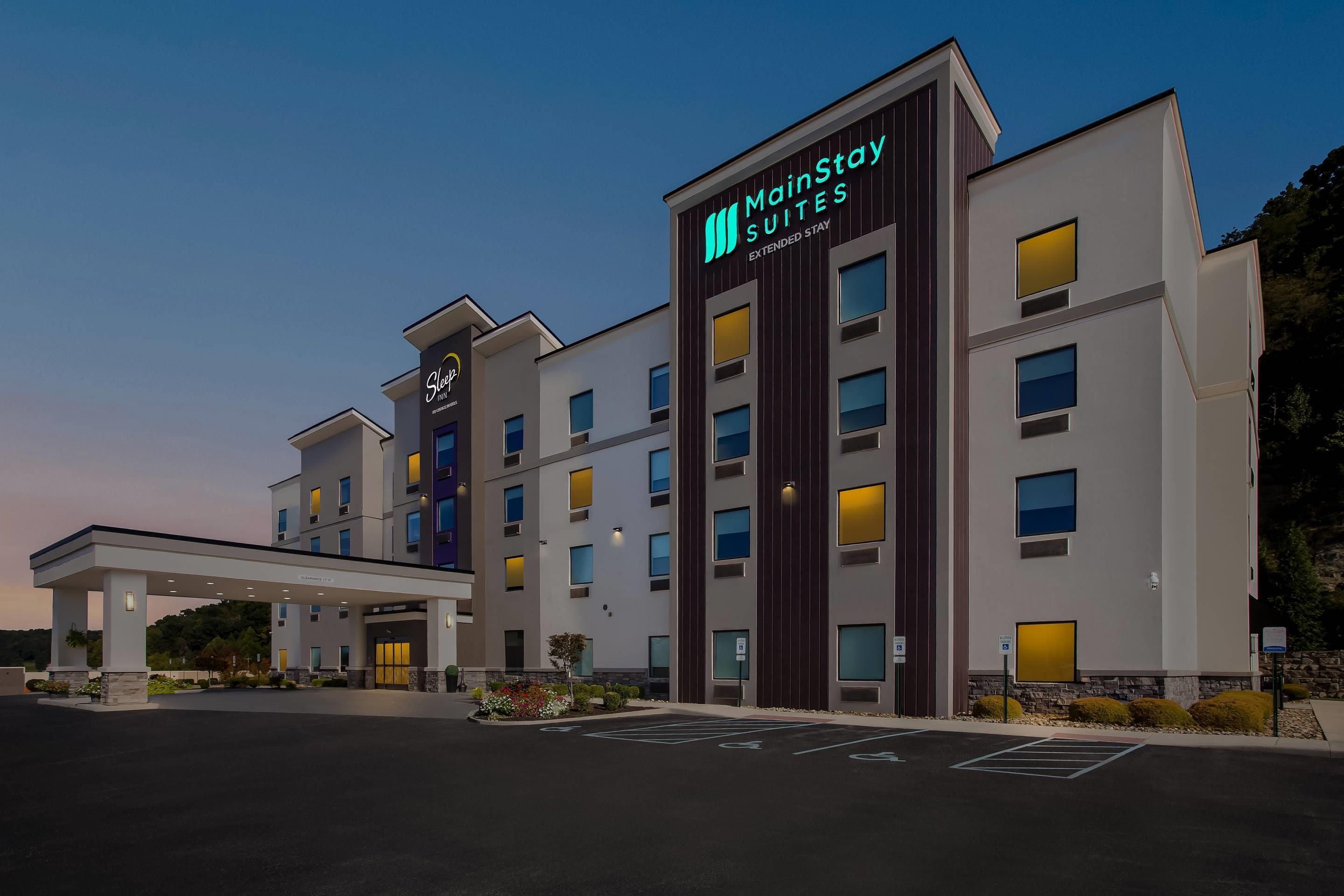 A MainStay Extended Stay hotel with a modern facade, multiple entry points, and a parking lot.