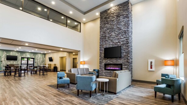A spacious lobby with a high ceiling, a stone accent wall, a flat-screen TV, and comfortable seating areas. - Sleep Inn Winfield - Teays Valley (Hurricane)