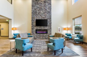 Un hall con chimenea de piedra, televisor de pantalla plana y sillones azules dispuestos alrededor de una mesa de centro.
