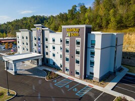 Un hotel MainStay Suites con diseño moderno, varios pisos y un estacionamiento con espacios para discapacitados.