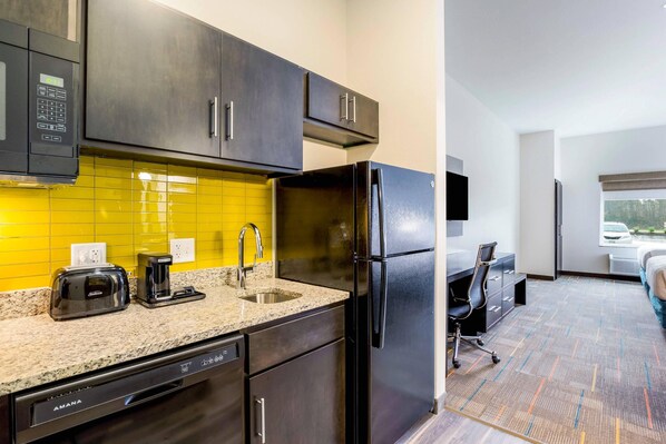 A modern kitchen with a built-in microwave, toaster, and coffee maker, a black refrigerator, and a sink. - MainStay Suites Winfield - Teays Valley (Hurricane)