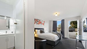 Una habitación de hotel moderna con una cama, mesita de noche y vistas al exterior.