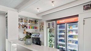 Zona de bar con estantes de bebidas alcohólicas, un refrigerador de Coca-Cola y una máquina de café.