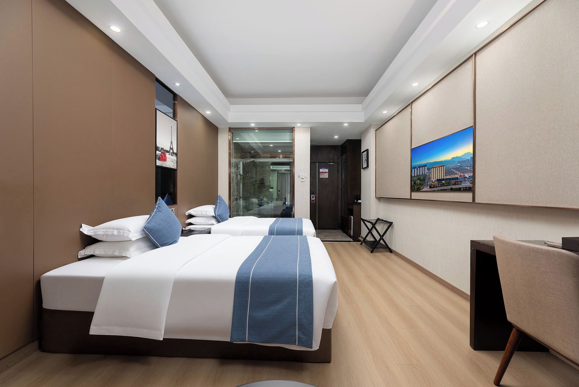 Una habitación de hotel moderna con una cama grande, un escritorio y vistas a un paisaje urbano.
