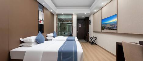 Hotelkamer met twee bedden, een bureau, een stoel, een schilderij aan de muur en uitzicht op de stad.