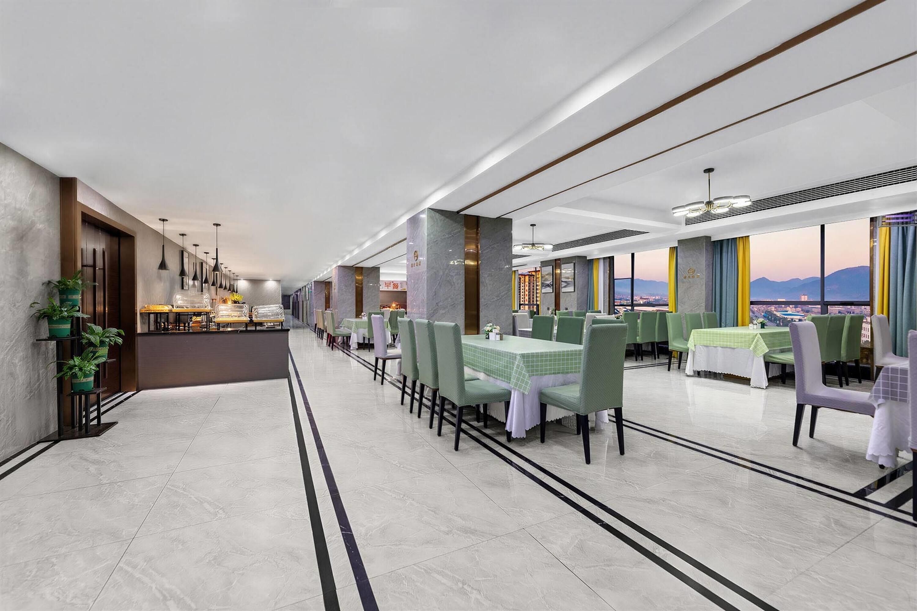 Ein modernes Restaurant mit einer langen Theke, grünen Stühlen und Blick auf die Stadt.