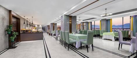 Ein modernes Restaurant mit einer langen Theke, grünen Stühlen und Blick auf die Stadt.