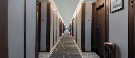 Un couloir d’hôtel avec de nombreuses portes, une moquette à motifs et une poubelle.