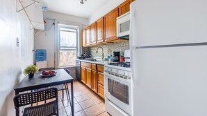 Una cucina compatta con mobili in legno, un frigorifero bianco e un fornello.