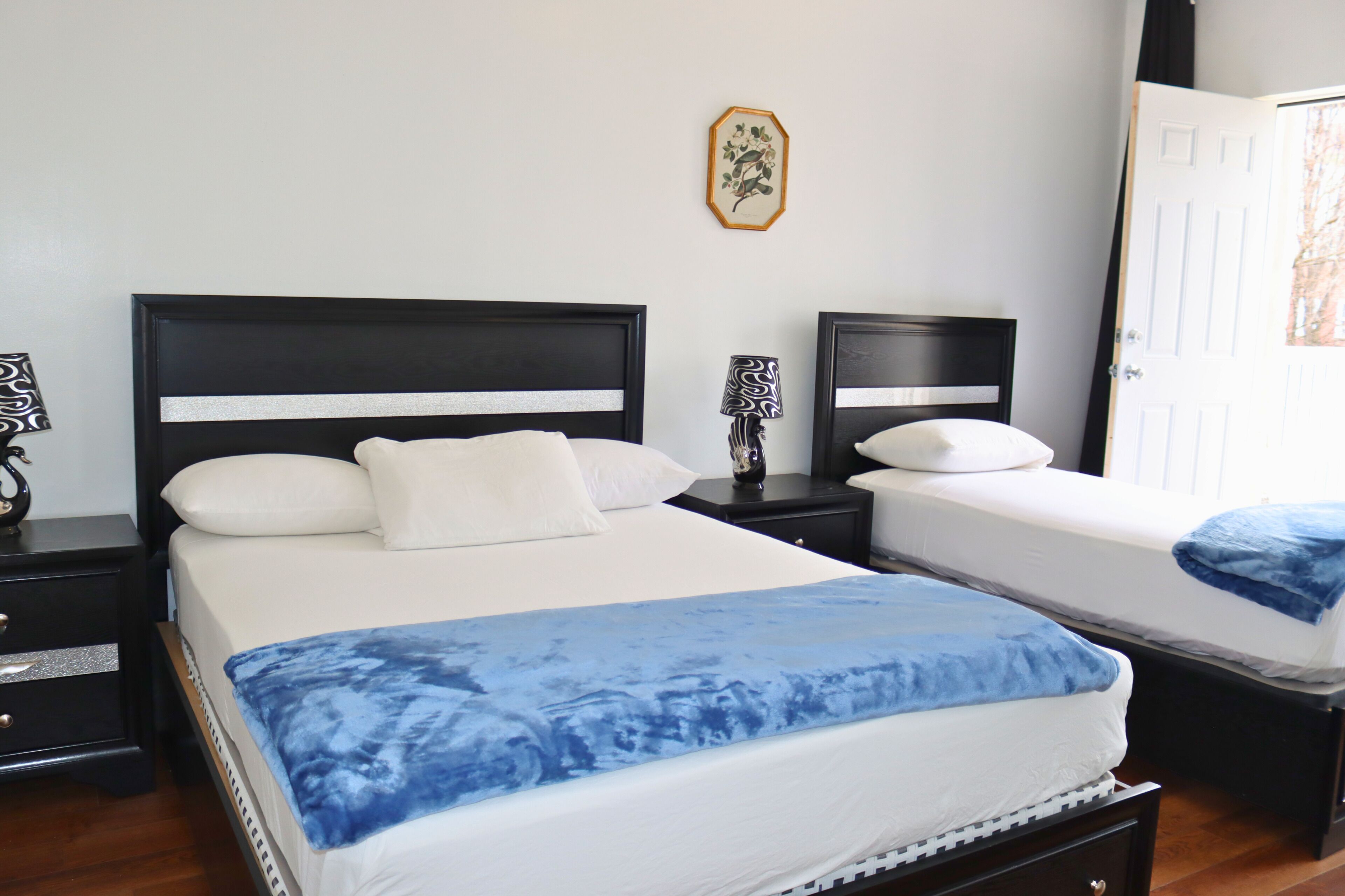 Un dormitorio con dos camas, una mesita de noche con lámpara y una puerta.