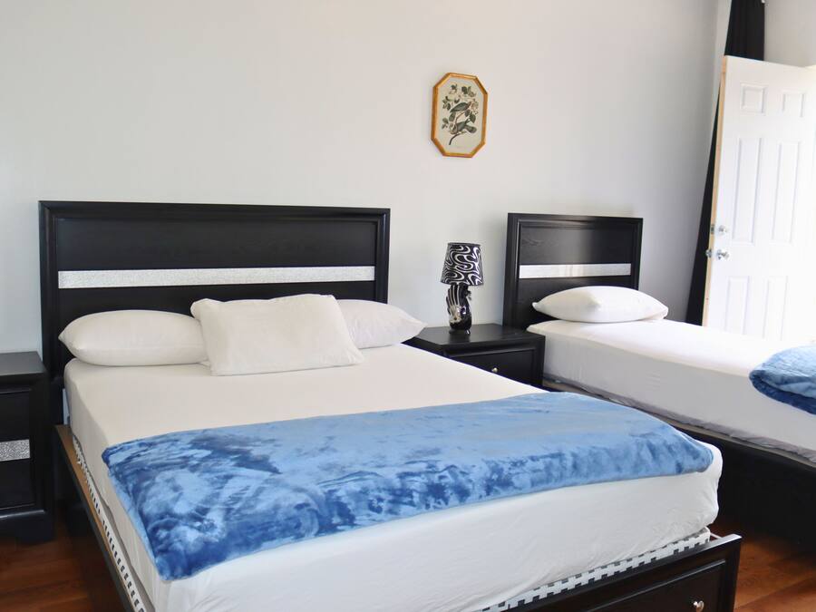 Un dormitorio con dos camas, una mesita de noche con lámpara y una puerta.