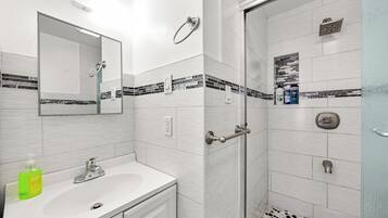 A modern bathroom with a white sink, mirror, and shower.