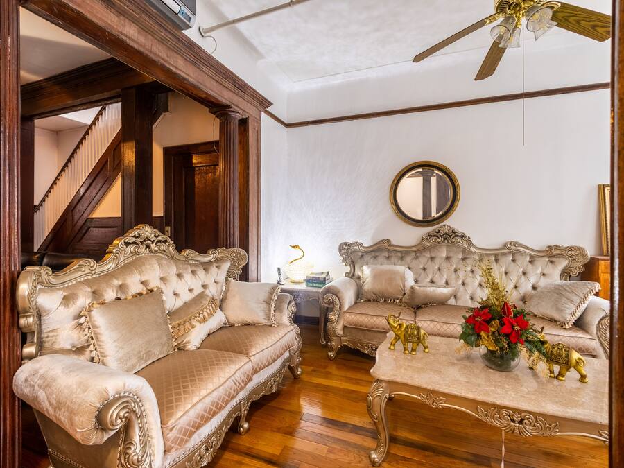 A room with two ornate sofas, a coffee table with a vase of flowers, and a round mirror on the wall.