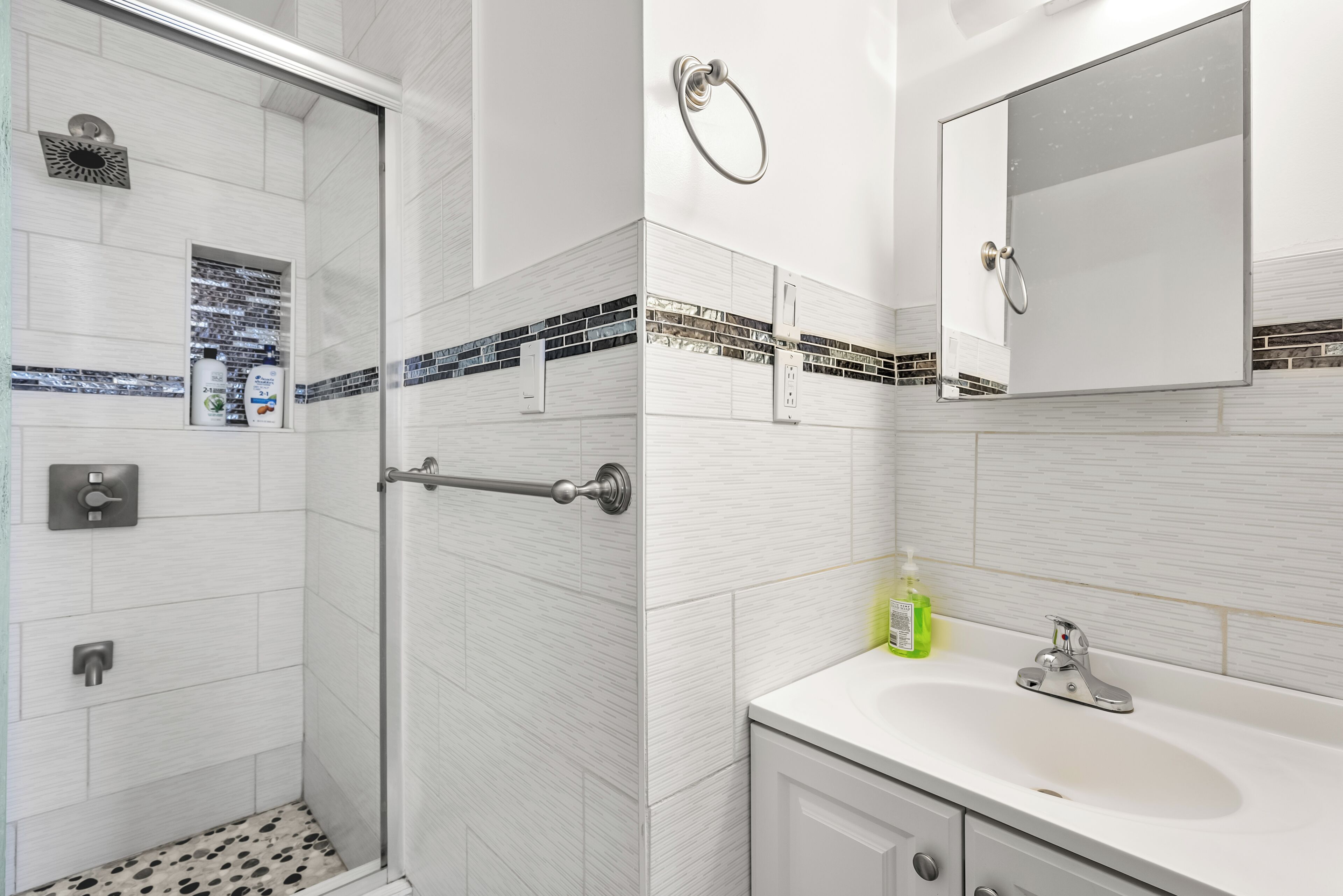 A modern bathroom with a shower, a sink, and a mirror.