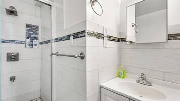 A modern bathroom with a shower, a sink, and a mirror.