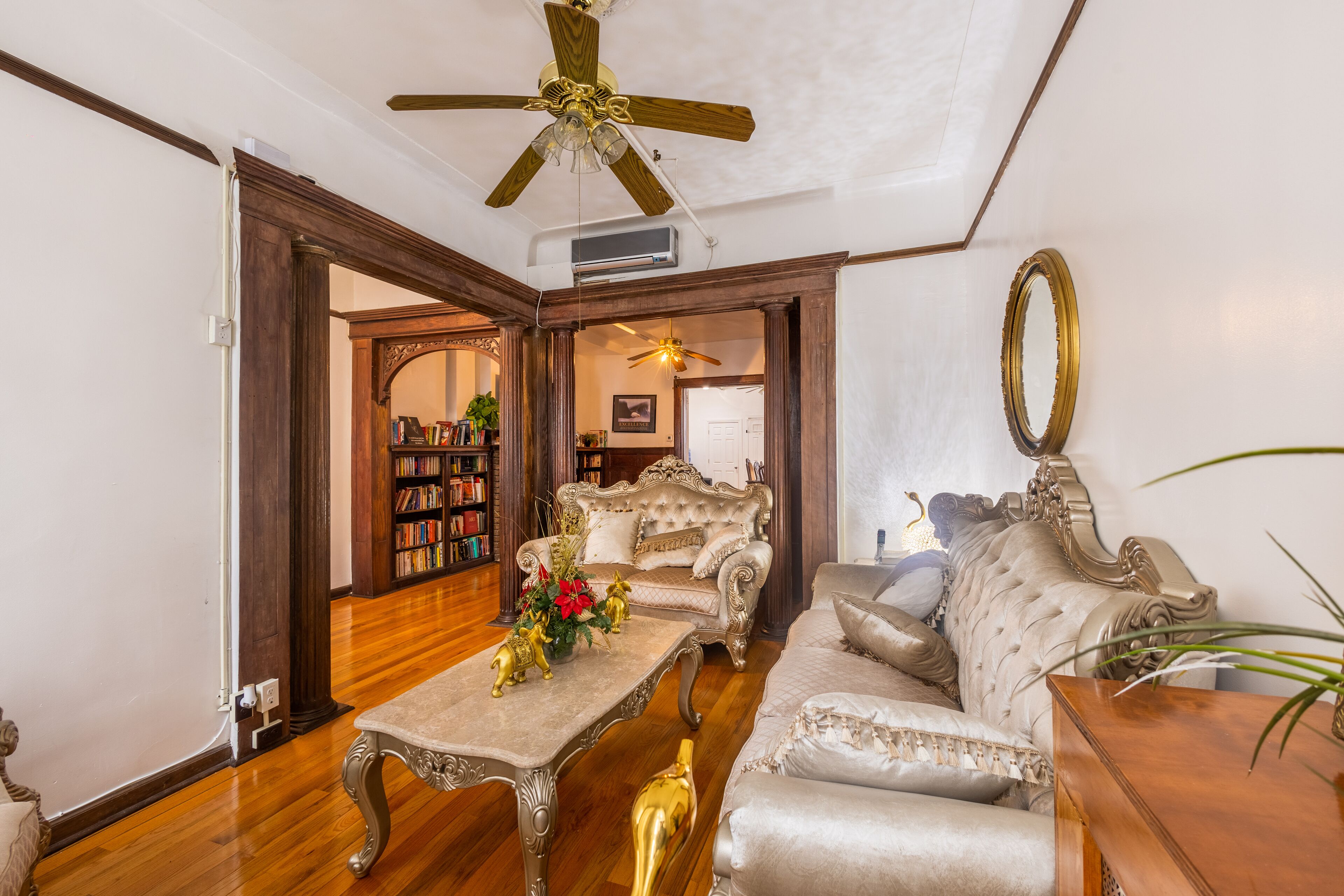 A spacious living room with a high ceiling fan, a fireplace, and a large window.