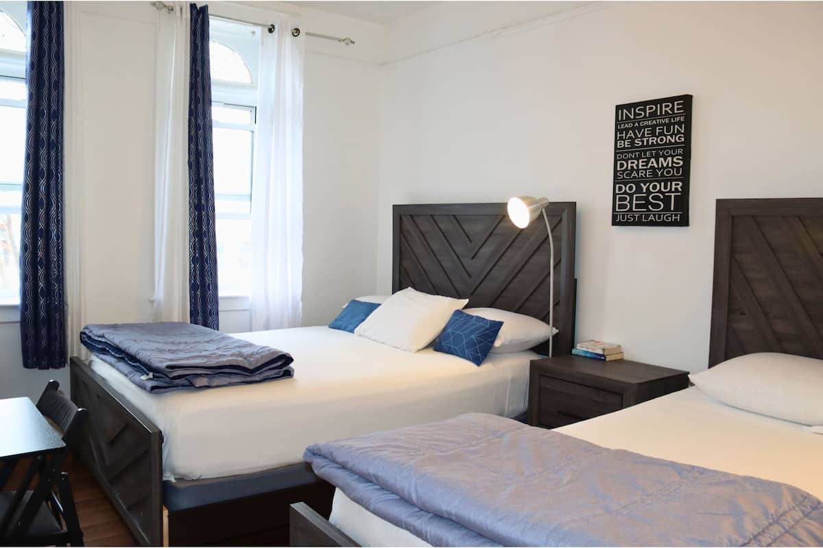 A hotel room with two beds, a desk, and a nightstand.