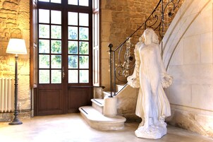 Una estatua de una mujer en una escalera con una pared de piedra y una puerta de madera.