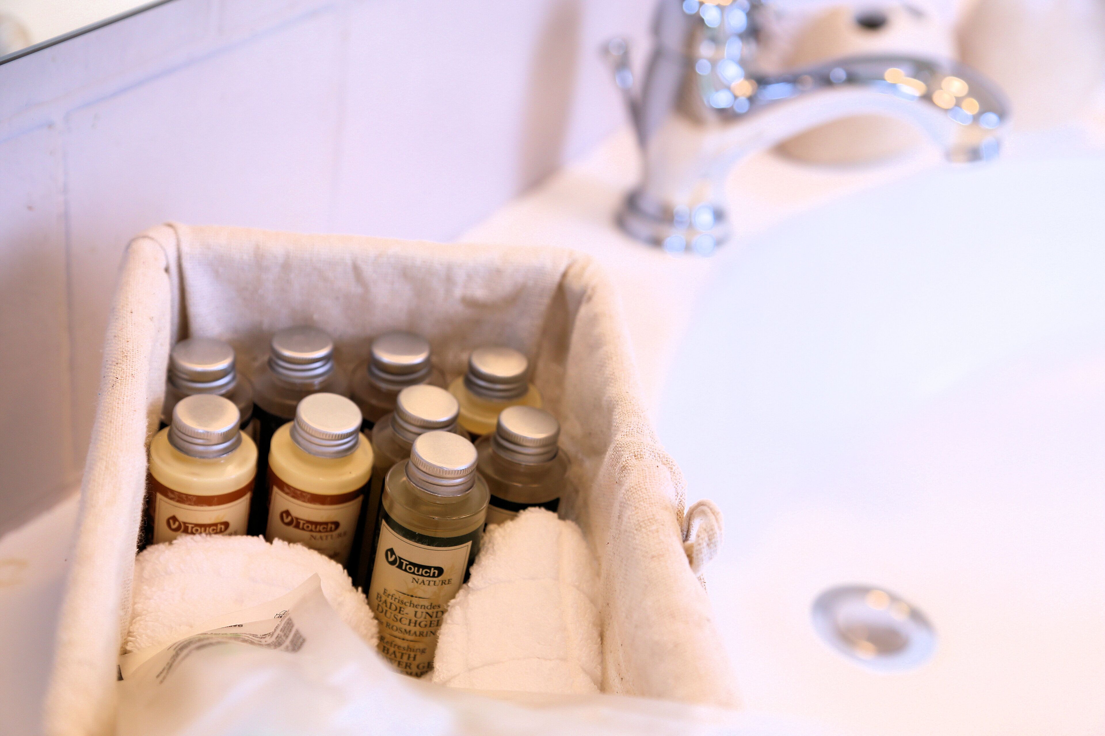 Un lavabo de salle de bain avec une serviette et des flacons de produits de la marque Touch Nature.