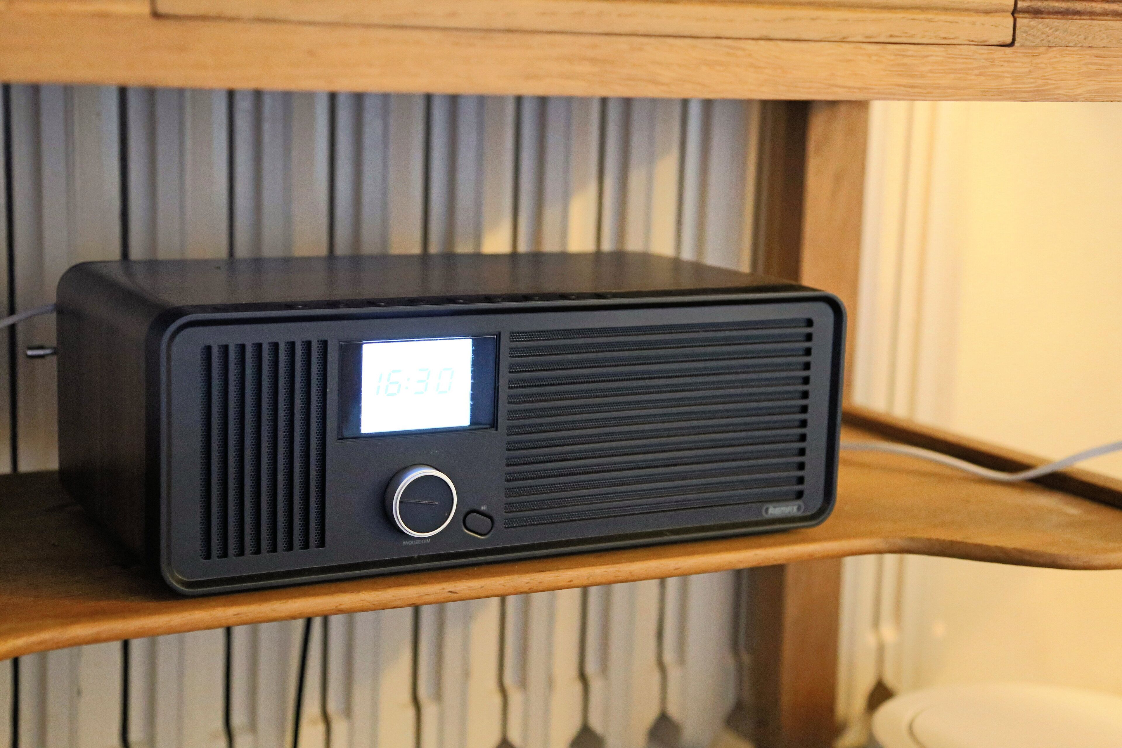 Une radio noire posée sur une étagère en bois.
