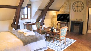 Une chambre à coucher avec un lit, deux chaises, une table, un téléviseur et une cheminée.