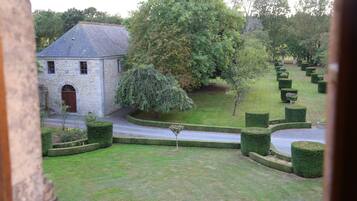 A stone building with a small garden, a tree, and neatly trimmed hedges.