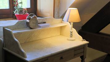 A marble desk with a lamp, a clock, and a potted plant by a window.