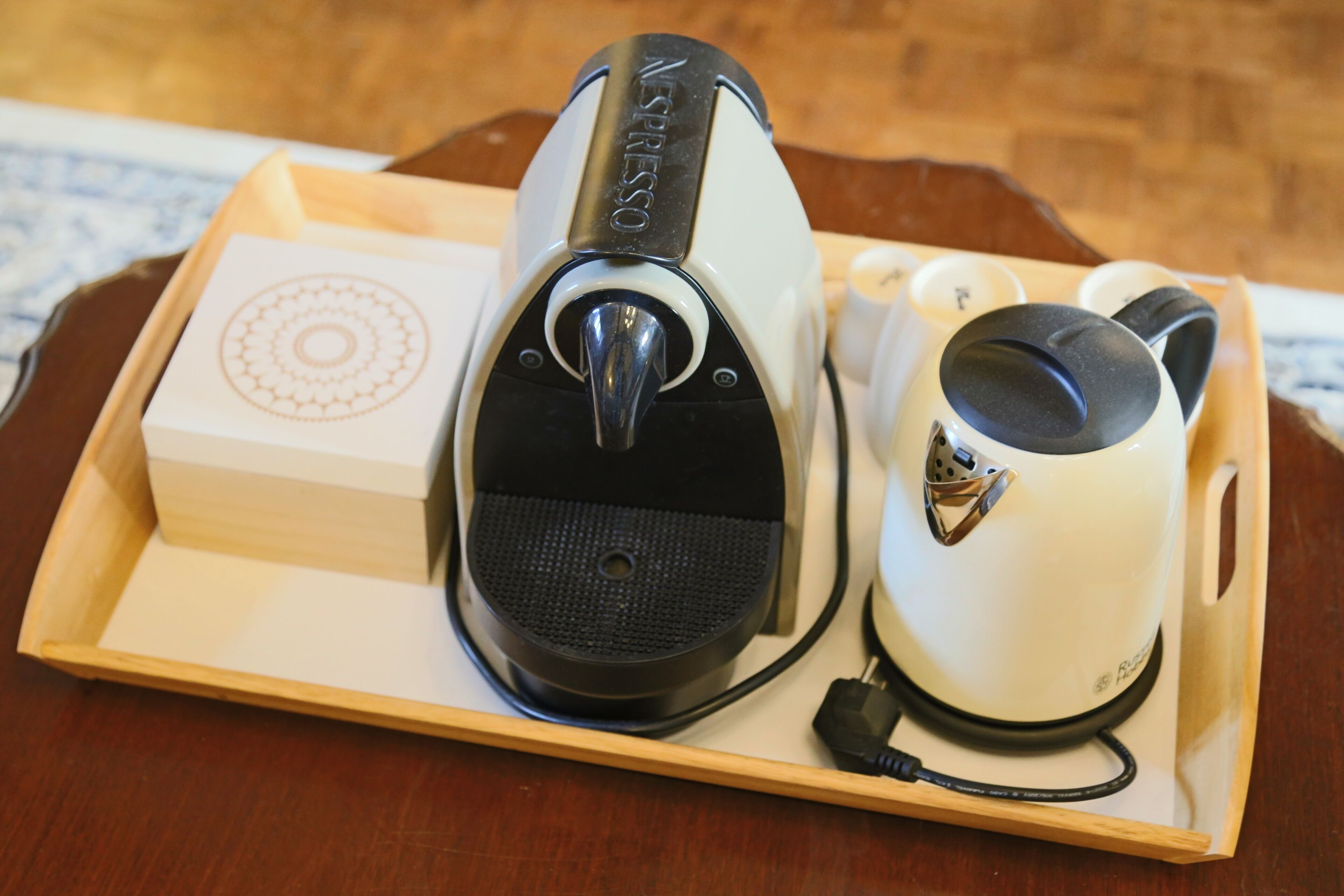 Un plateau avec une machine à café, une boîte et une tasse.