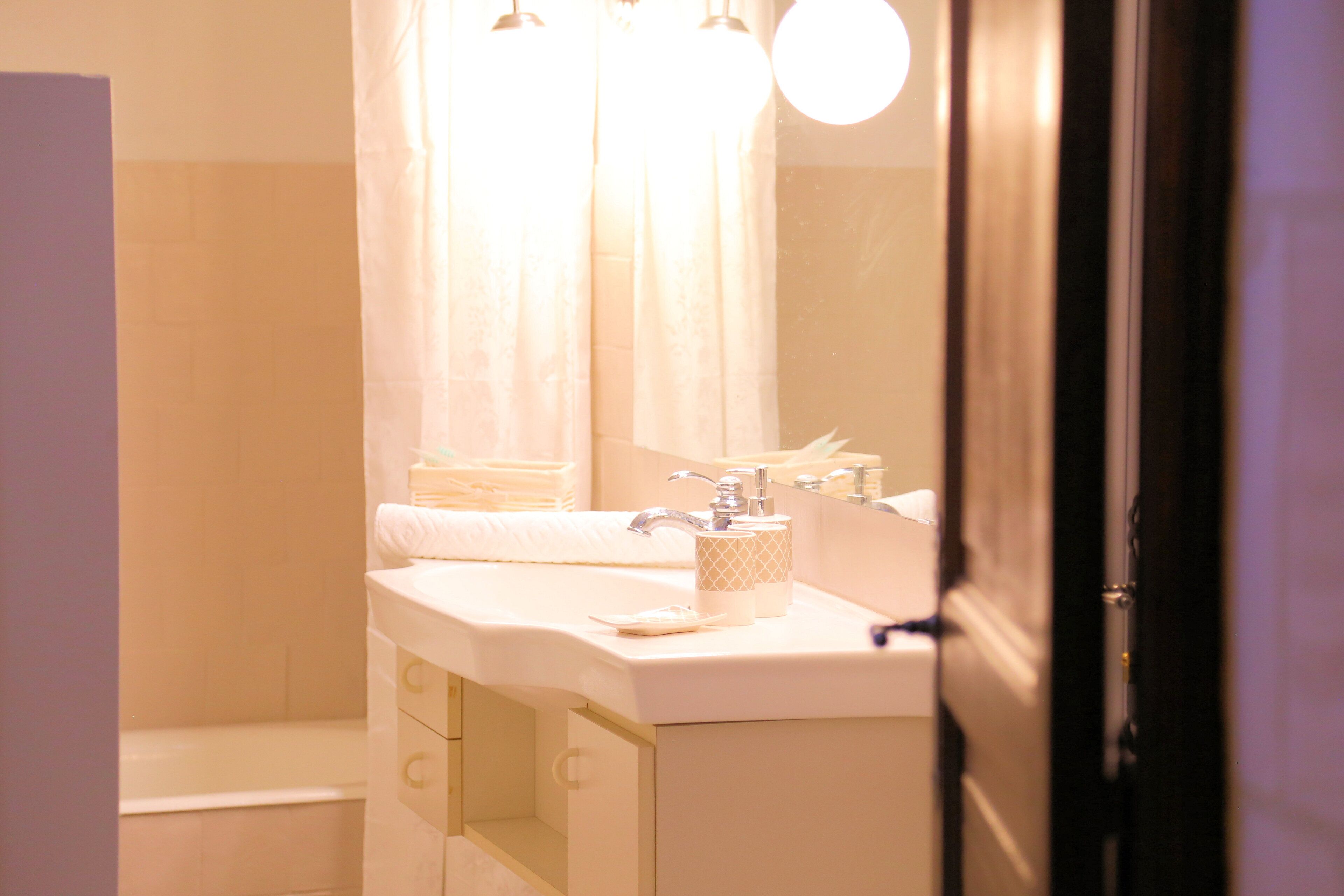 Un baño con lavamanos blanco, un espejo y una cortina de ducha.