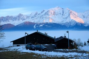 Un bâtiment doté d’un espace de stationnement et offrant une vue sur des montagnes enneigées.