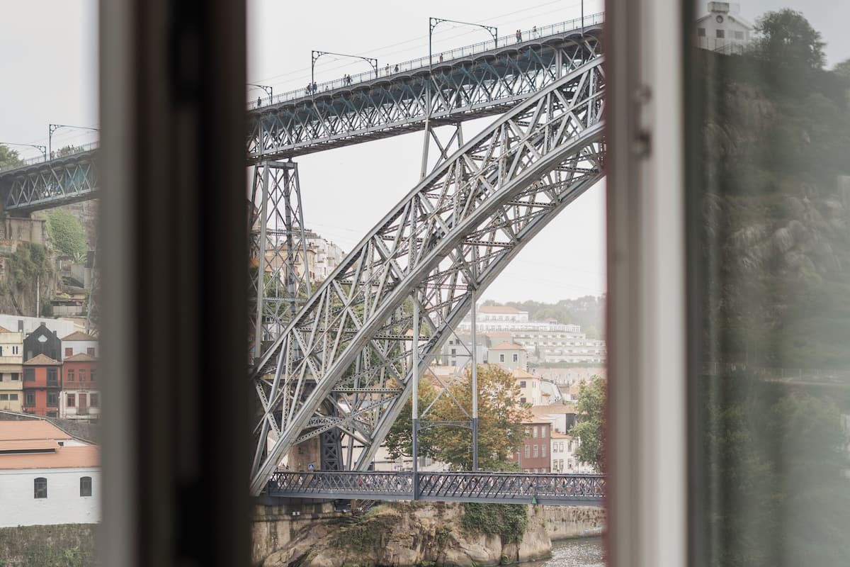 A view through a window of a river with a bridge and a boat.